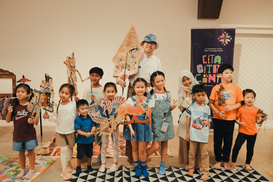A memorable moment from the storytelling session as children hold up unique traditional puppets for a group photo.